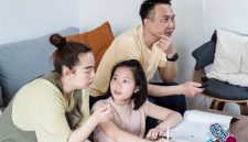 Seorang ibu mendampingi putrinya belajar dengan penuh kesabaran di meja belajar rumah yang tertata rapi. Suasana yang tenang dan penuh kasih sayang terbukti meningkatkan fokus serta kepercayaan diri anak.